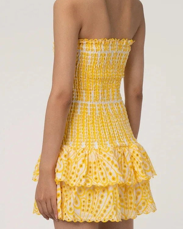 Yellow strapless dress with ruffled layers on a plain background