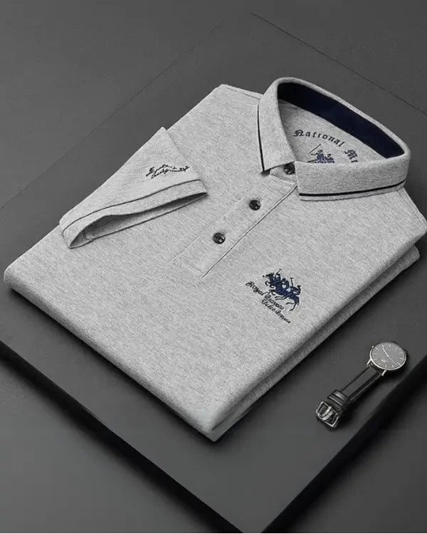 Folded gray polo shirt with brand logo on a dark surface