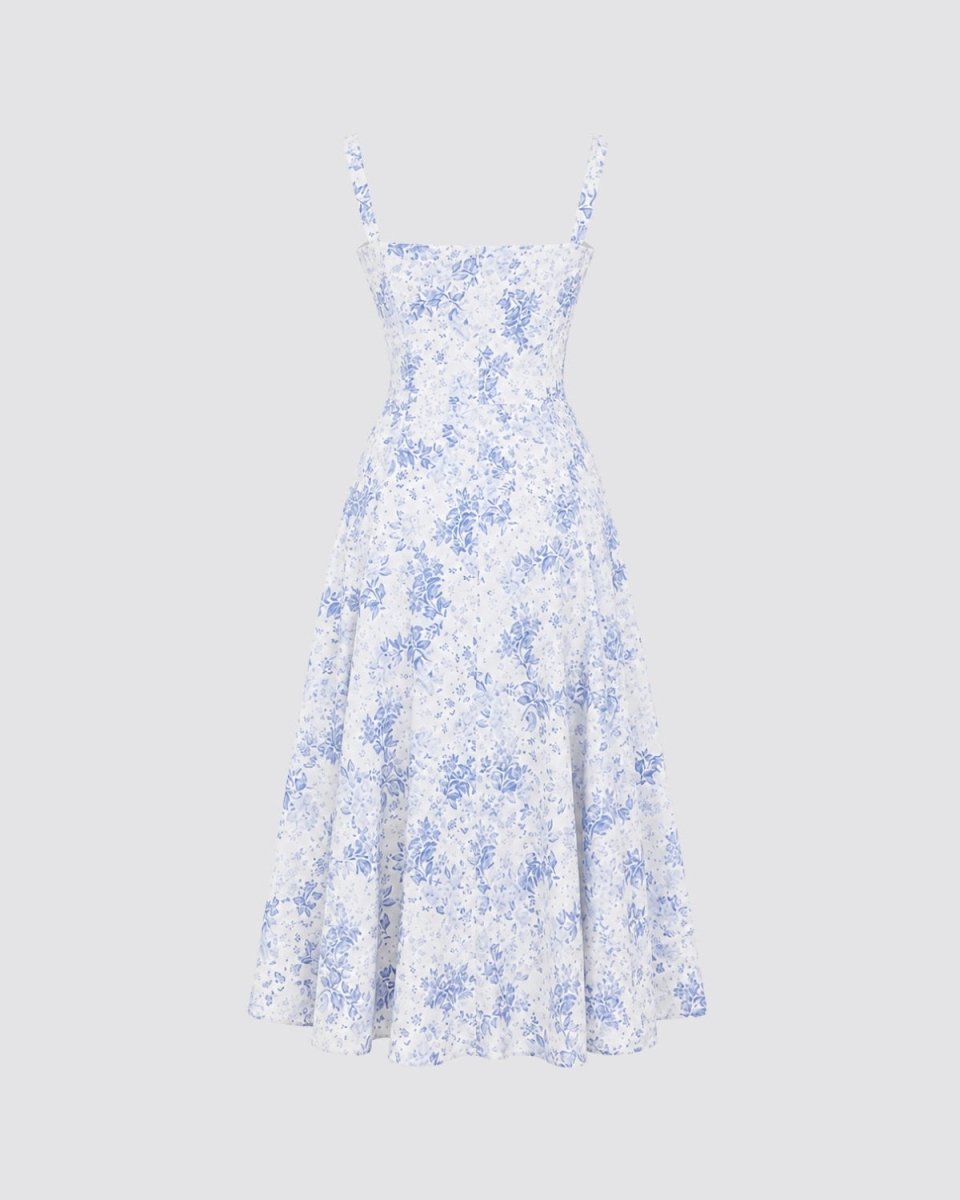 A sleeveless white midi dress with a blue floral pattern and thin spaghetti straps, shown against a solid light gray background.