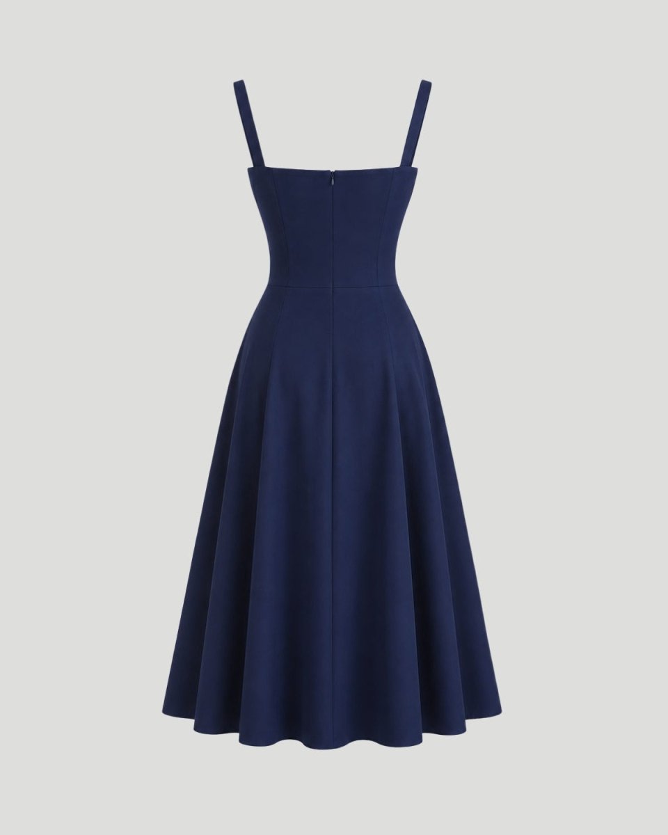 A navy blue swing dress with thin shoulder straps, a structured square neckline, and a flared skirt, shown against a solid light gray background.