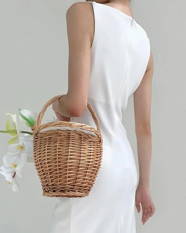 Person wearing a white dress holding a wicker basket against a light background