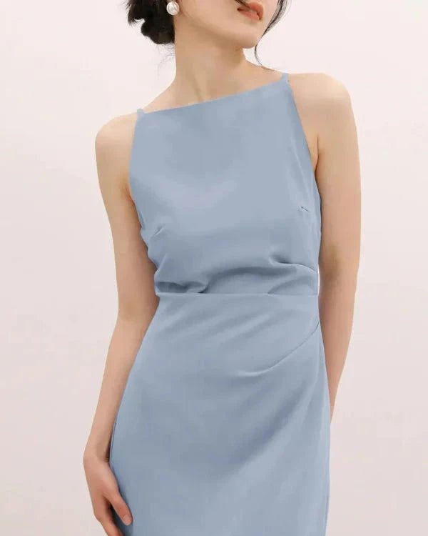 Woman wearing a light blue one-shoulder dress against a plain background
