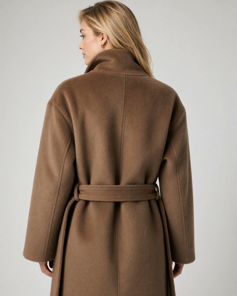A woman shown from the back wearing a brown wool coat with a matching waist belt, photographed against a plain light gray studio background.