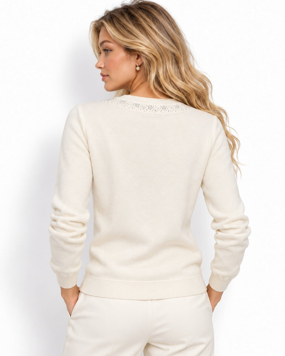 A woman shown from the back wearing a cream-colored knit sweater with delicate lace detailing around the crew neckline, paired with matching cream pants, against a plain white studio background.