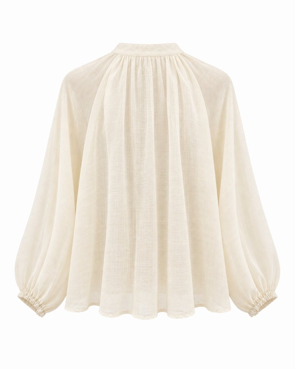 An apricot long-sleeve blouse with a gathered high neckline, pleated front, and elasticized cuffs, shown against a plain white background.