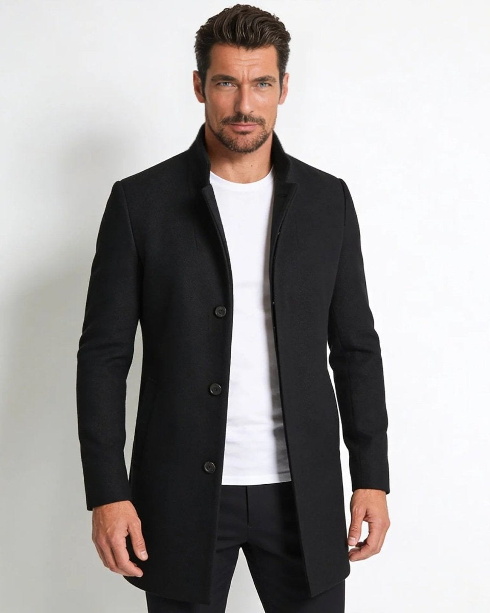 Male model wearing the Archie black wool stand collar overcoat, buttoned, styled with a white t-shirt and black trousers against a white background.