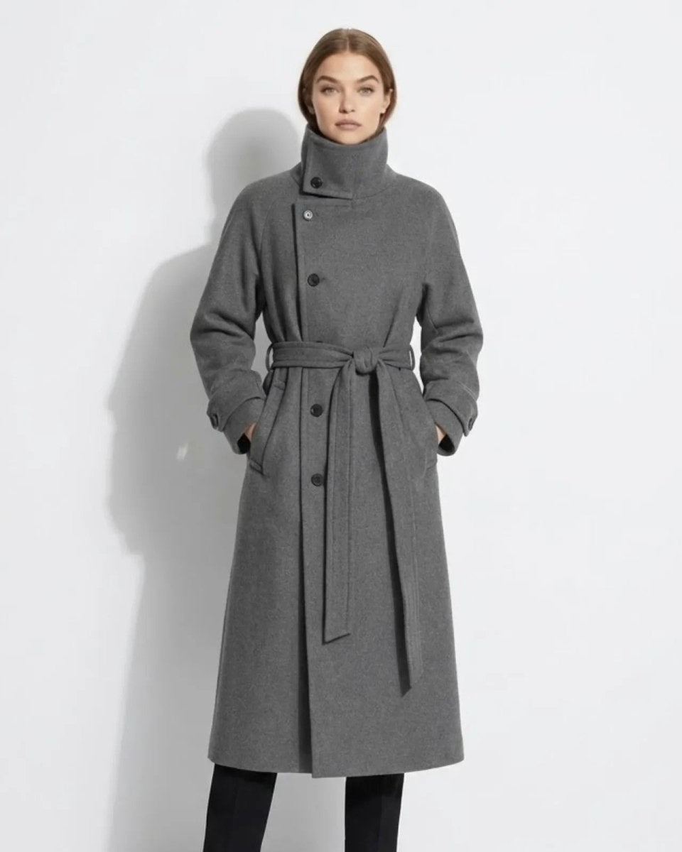 Model wearing the grey Ashley funnel neck wool coat with the belt tied, showcasing the asymmetrical button closure and long silhouette.