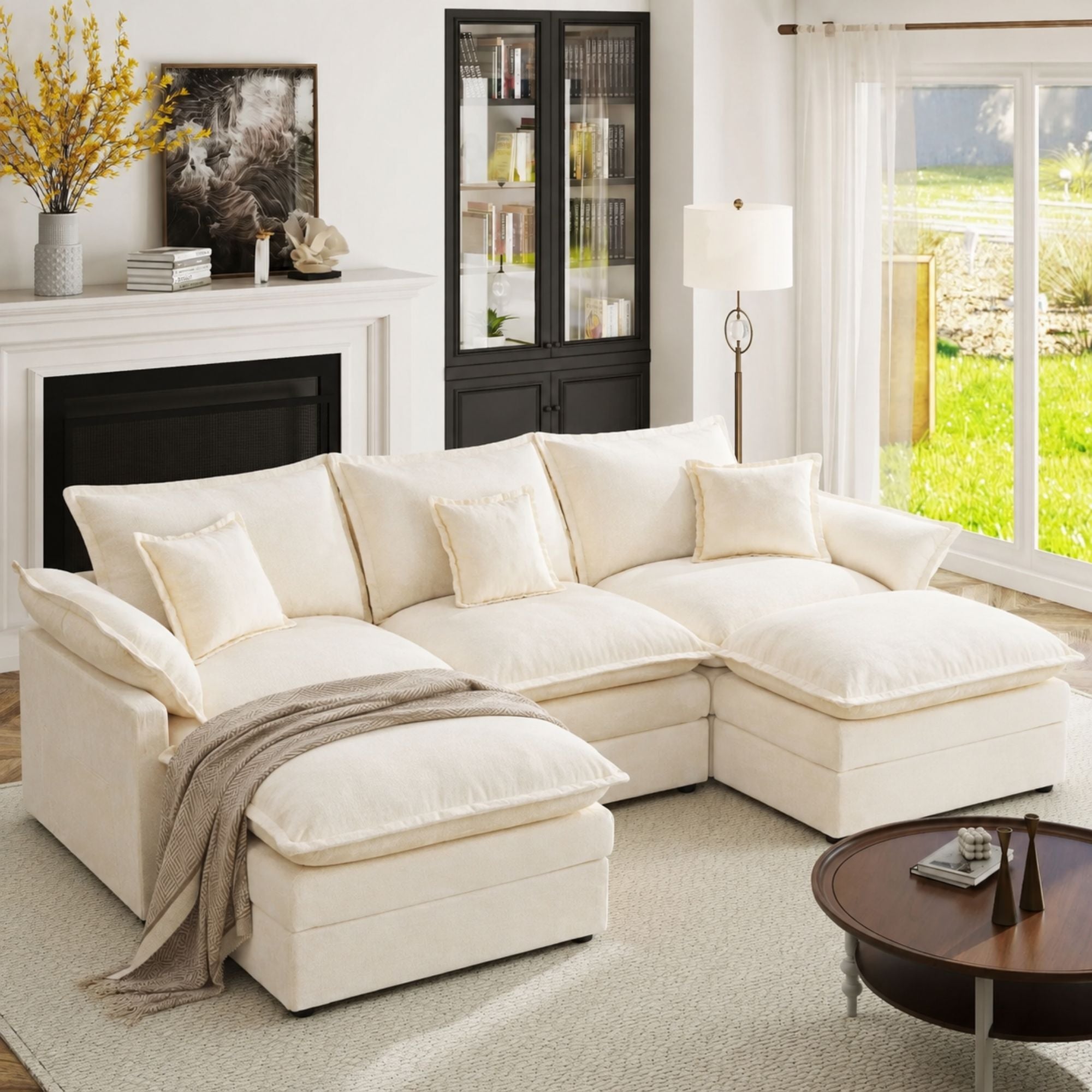 An off-white sectional sofa with matching throw pillows and a chaise lounge, styled in a bright, modern living room with a fireplace, window view, and a neutral throw blanket.