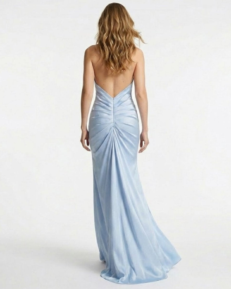 Back view of a model in the light blue Beverly satin gown, highlighting the completely open back and ruched detail at the waist.