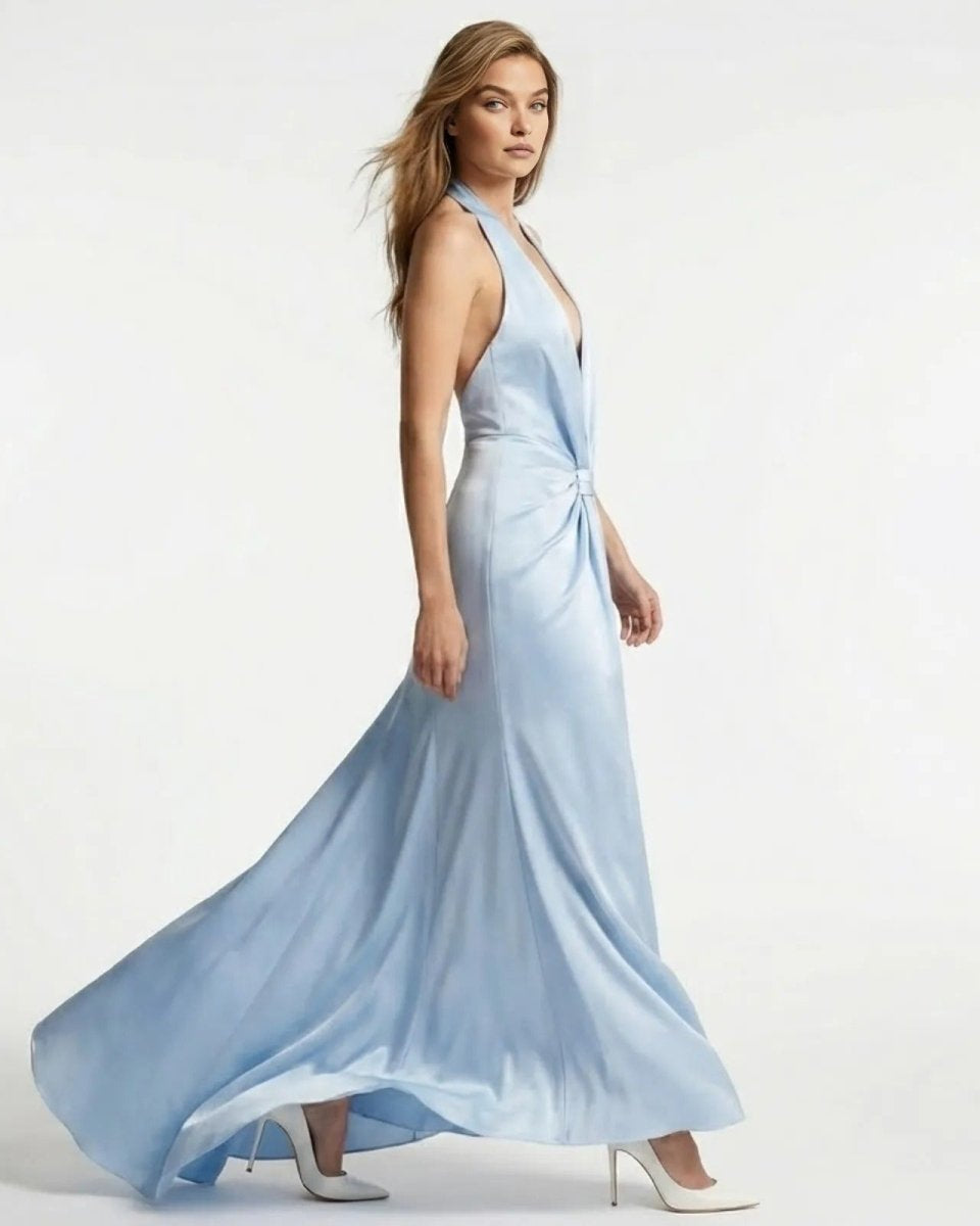 Side view of a model walking in the light blue Beverly satin halter gown, showing the dress's flow and open-back design.