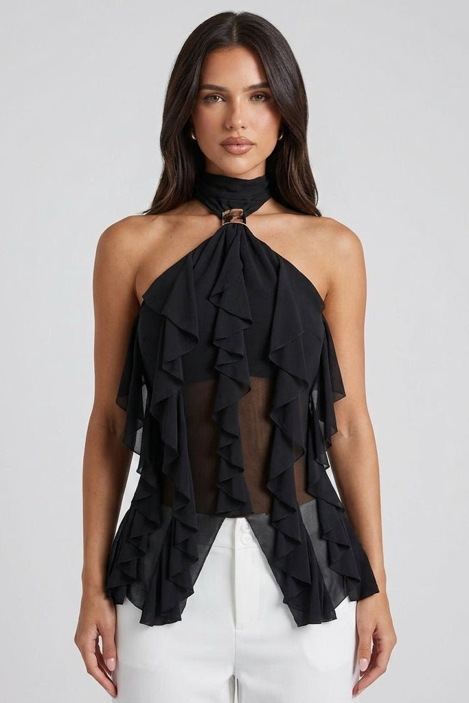 Front view of brunette model wearing Fenlo Form black sheer chiffon ruffle halter top with gold neck hardware styled with tailored white pants.