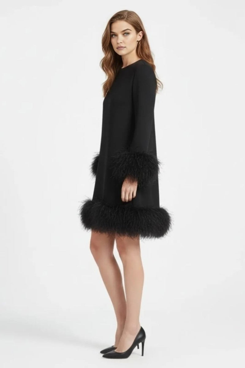Side profile of a model in a black A-line mini dress featuring dramatic ostrich feather cuffs and hem, styled with black stiletto heels.