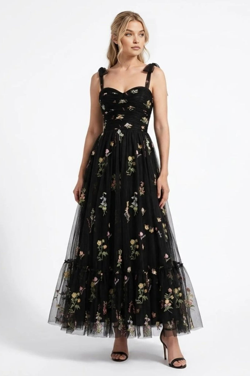Woman wearing Fenlo Form black floral embroidered tulle maxi dress with sweetheart neckline and tie straps, front full length view.