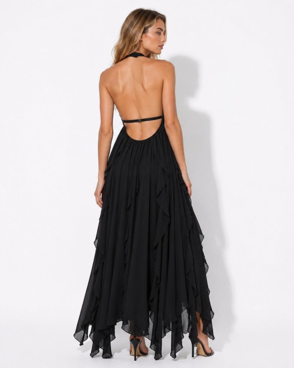 A woman modeling a black halter-neck maxi dress from the back, featuring a ruffled tiered skirt and open back design, set against a plain white studio background.