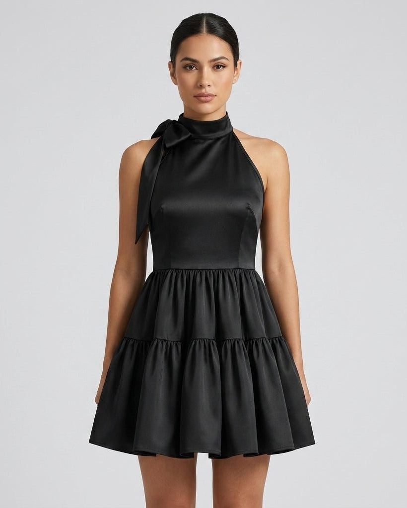 Close up front view of brunette model modeling the affordable luxury black sleeveless halter neck mini dress.