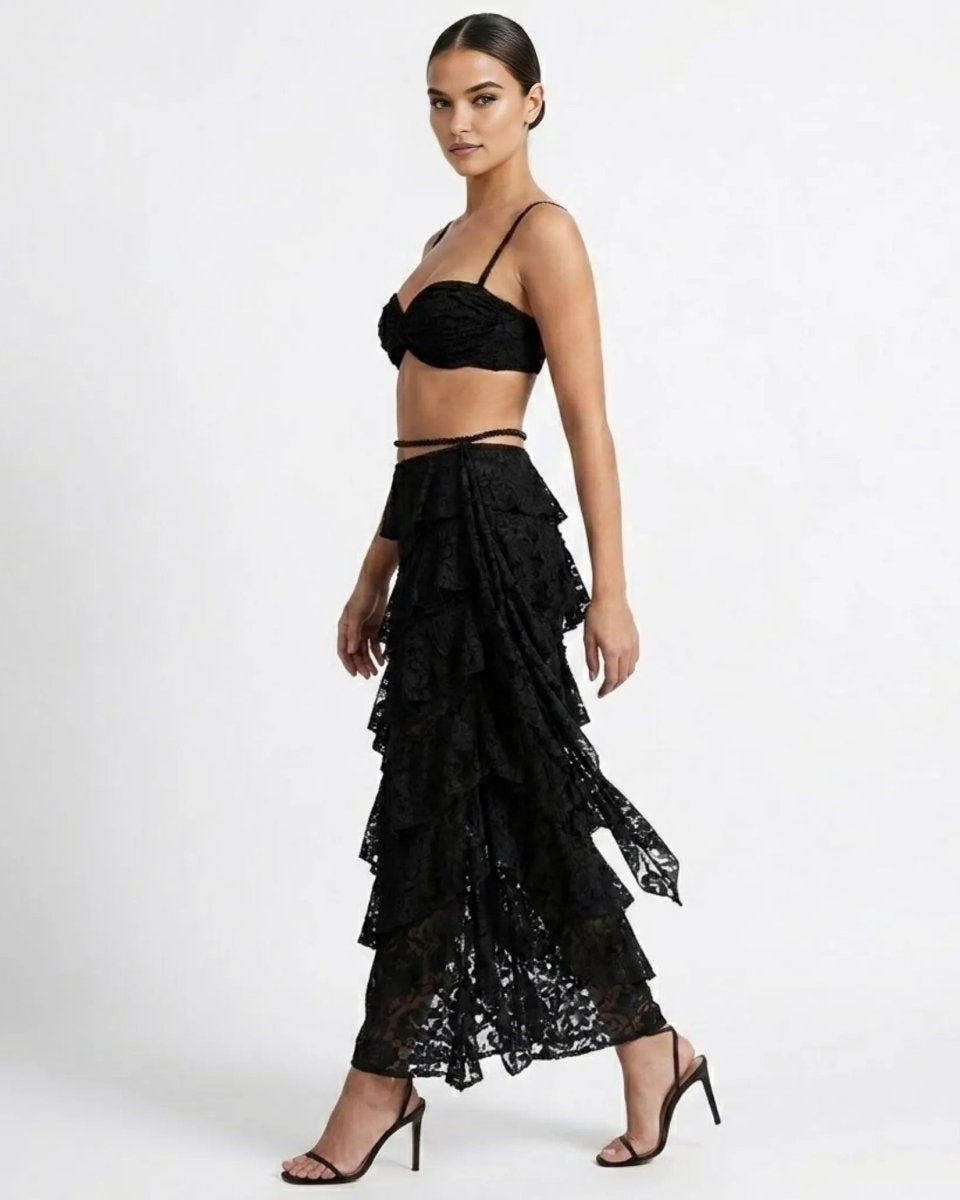 Side profile of woman modeling a black sheer lace asymmetrical tiered maxi skirt and ruched crop top