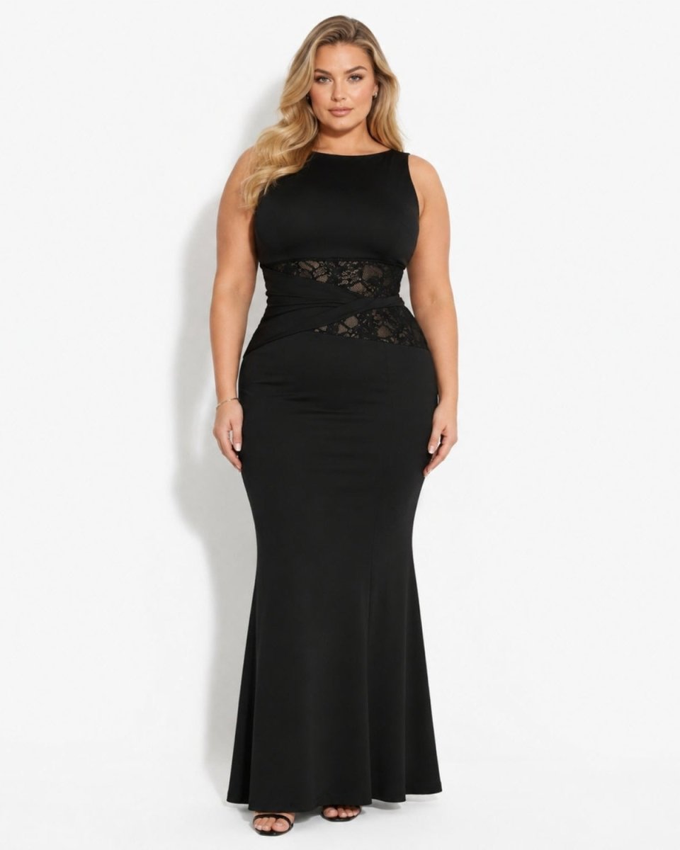 A woman modeling a sleeveless black floor-length gown with a fitted silhouette, lace waist detailing, and a flared skirt against a plain light gray studio background.
