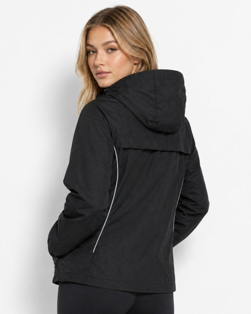 Back view of woman in black activewear jacket highlighting breathable back vent flap and reflective piping.