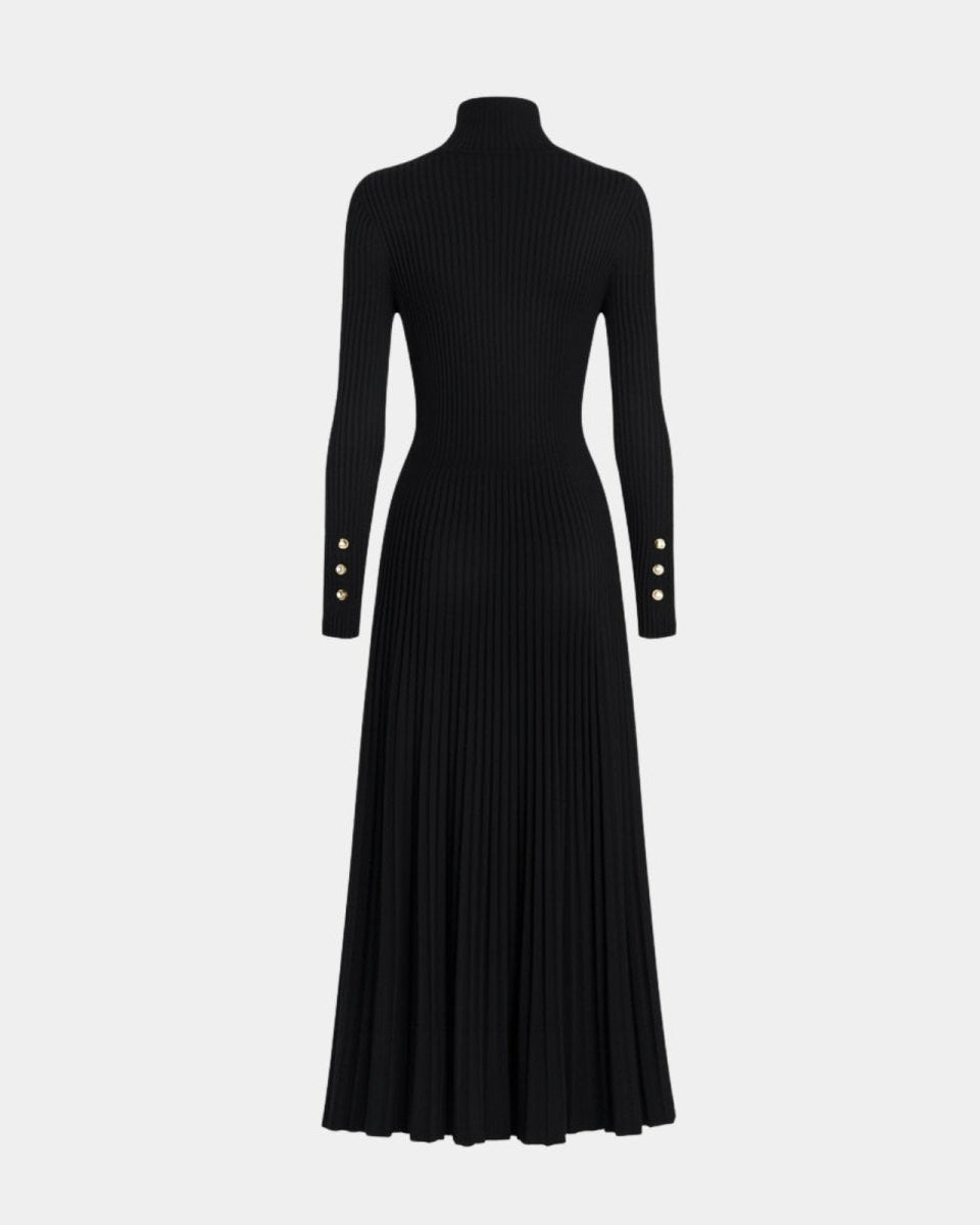 Flatlay of the black turtleneck dress emphasizing the ribbed knit texture, pleated skirt, and gold cuff buttons.