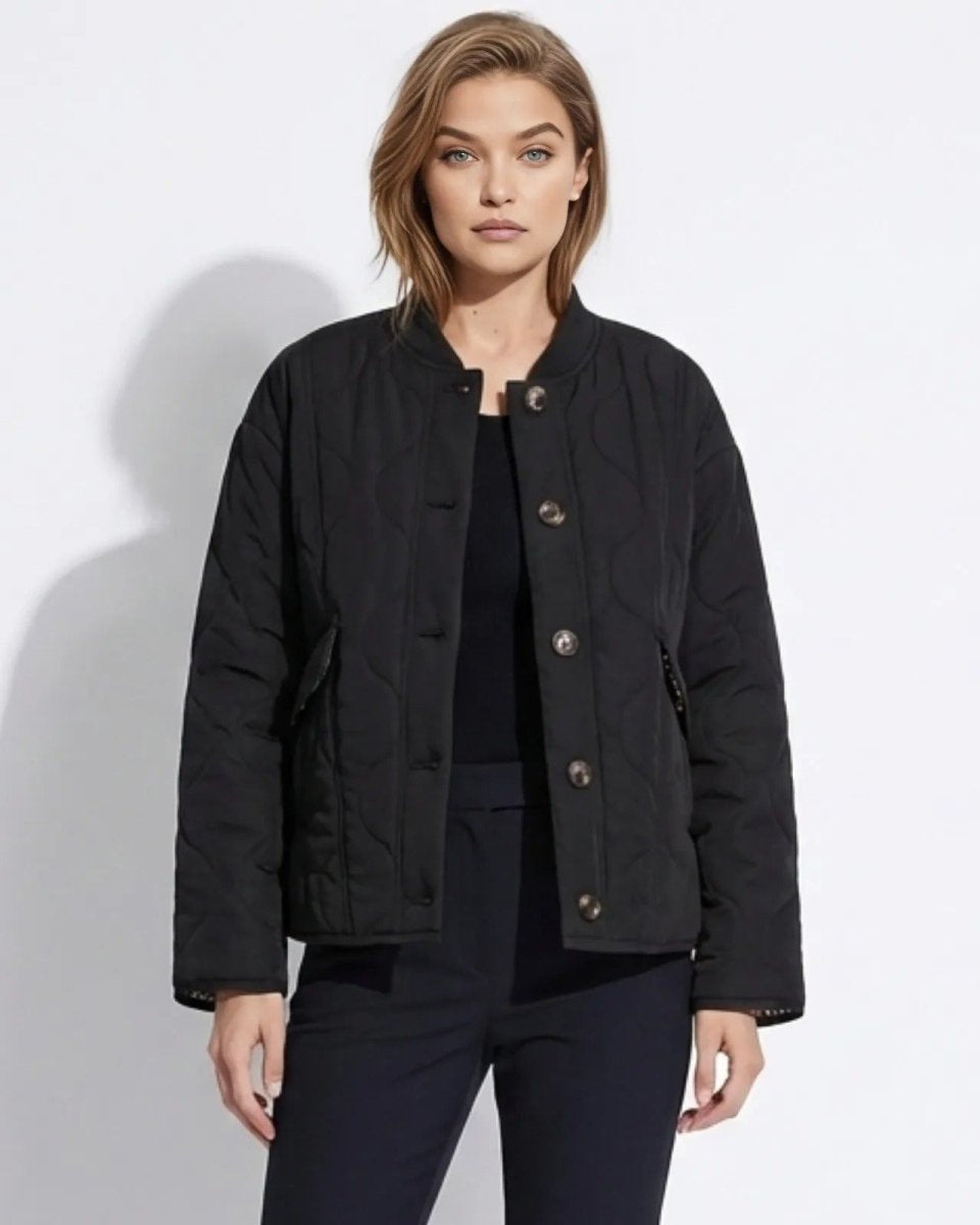 Model wearing the black collarless quilted liner jacket with button front, styled with black trousers.