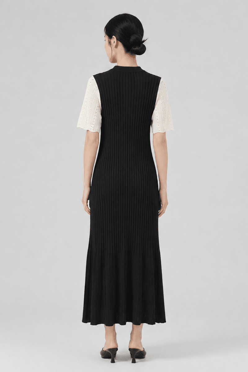Back view of female model wearing the Fenlo Form fitted black ribbed sweater dress showing the back silhouette and fluted hem.