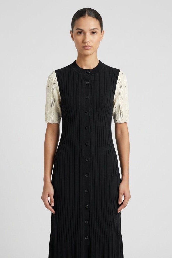 Close up view of the Fenlo Form black ribbed knit dress highlighting the high crew neck, front button details, and textured cream pointelle sleeves.