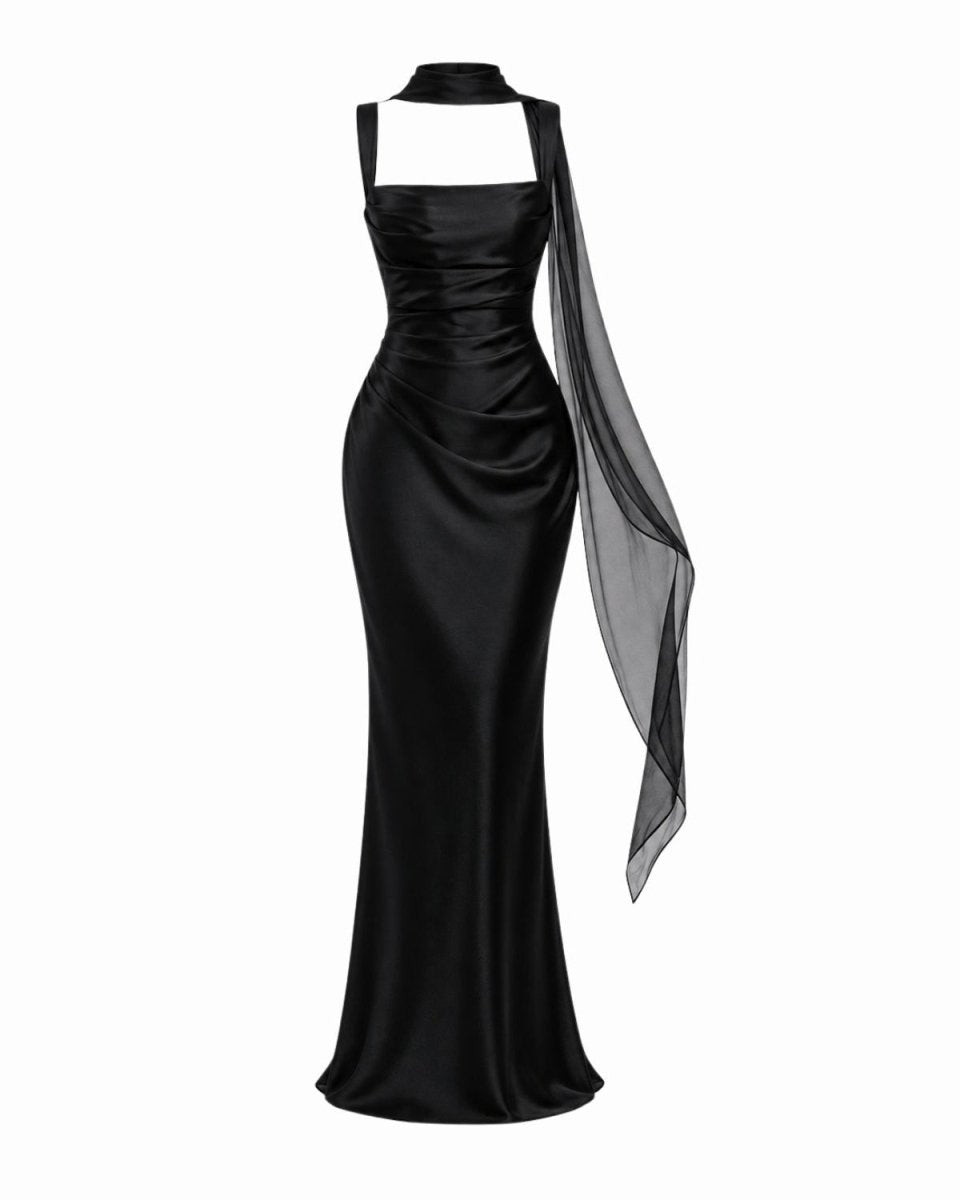 A black satin evening gown with a high neck, square neckline cutout, draped ruching, and a sheer black chiffon side drape, shown on a white background.