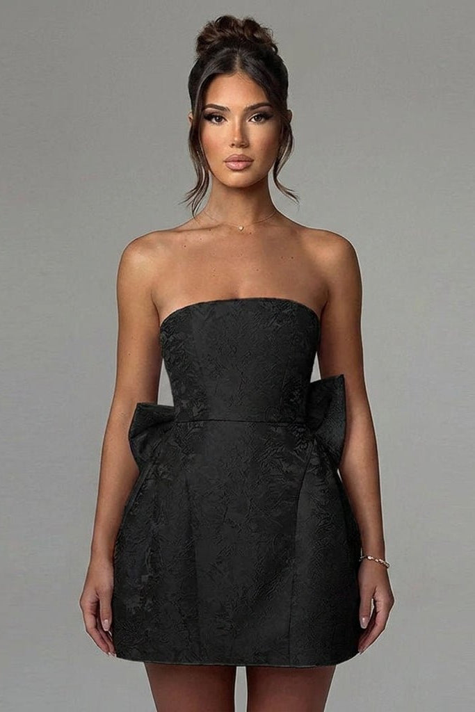 Close-up front view of the structured bodice and textured floral brocade fabric of the black strapless mini dress by Kouvr.