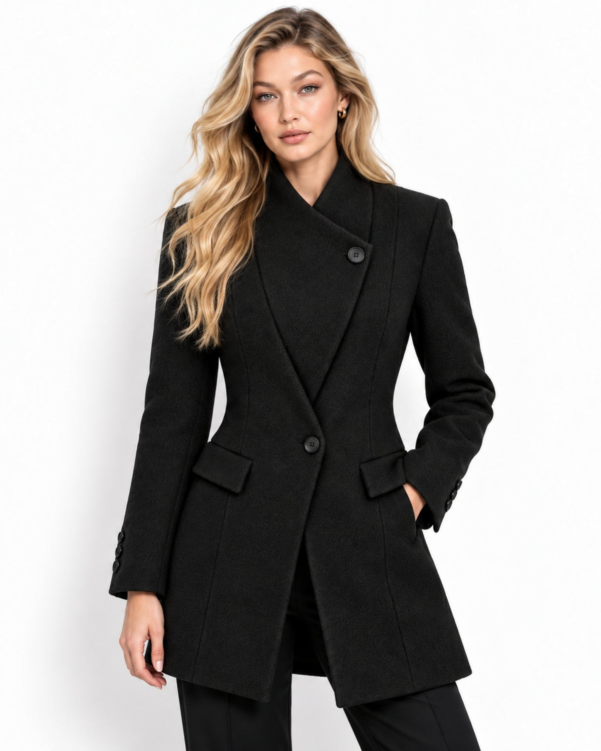 Woman wearing the tailored black wool wrap coat with asymmetrical single button closure and funnel neck, hands resting in flap pockets.