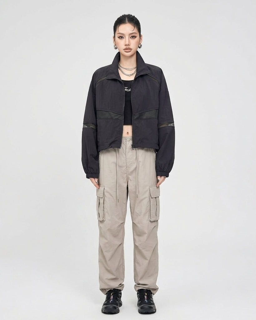 Fashion model wearing Kouvr black techwear zip up jacket styled with beige utility cargo pants
