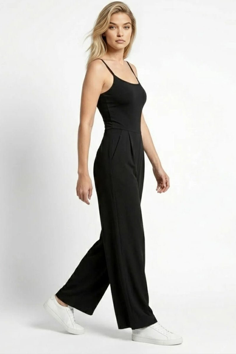 Side profile of woman walking in Fenlo Form black wide leg pleated jumpsuit