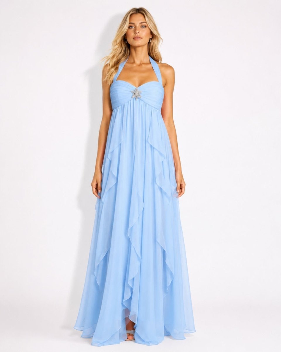A woman modeling a light blue halter-neck maxi dress with a ruched bodice and layered ruffle skirt, standing against a plain white studio background.