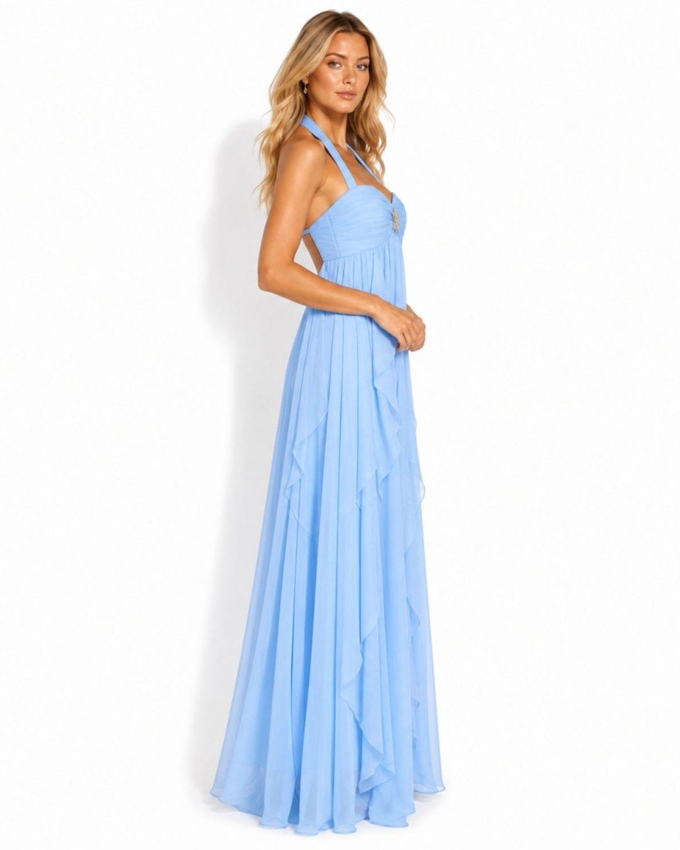 A woman modeling a light blue halter-neck maxi dress with a pleated, tiered skirt against a plain white background.