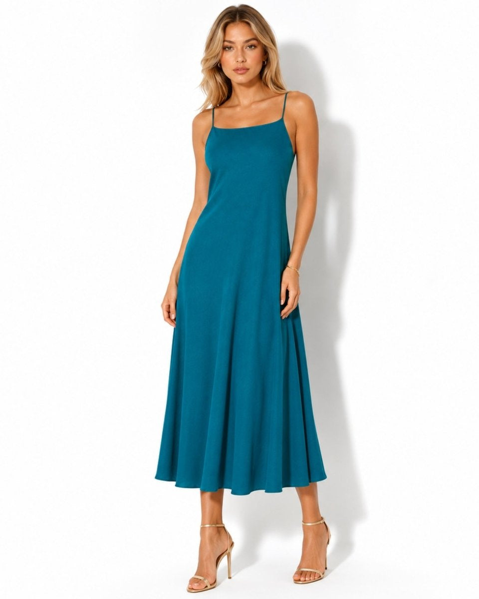 Fashion model wearing an elegant blue linen midi slip dress with a square neckline and gold heels facing forward.