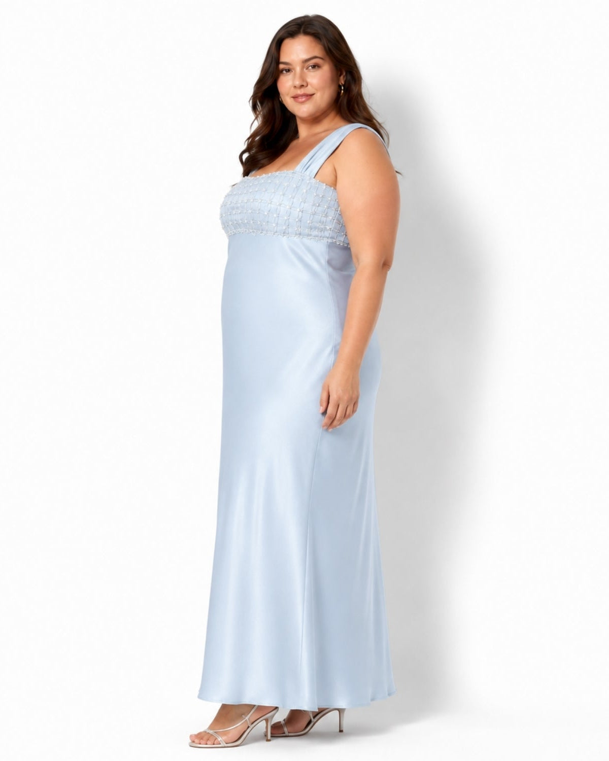 A woman modeling a light blue satin maxi dress with a textured lace bodice and one-shoulder straps, standing against a plain white studio background.