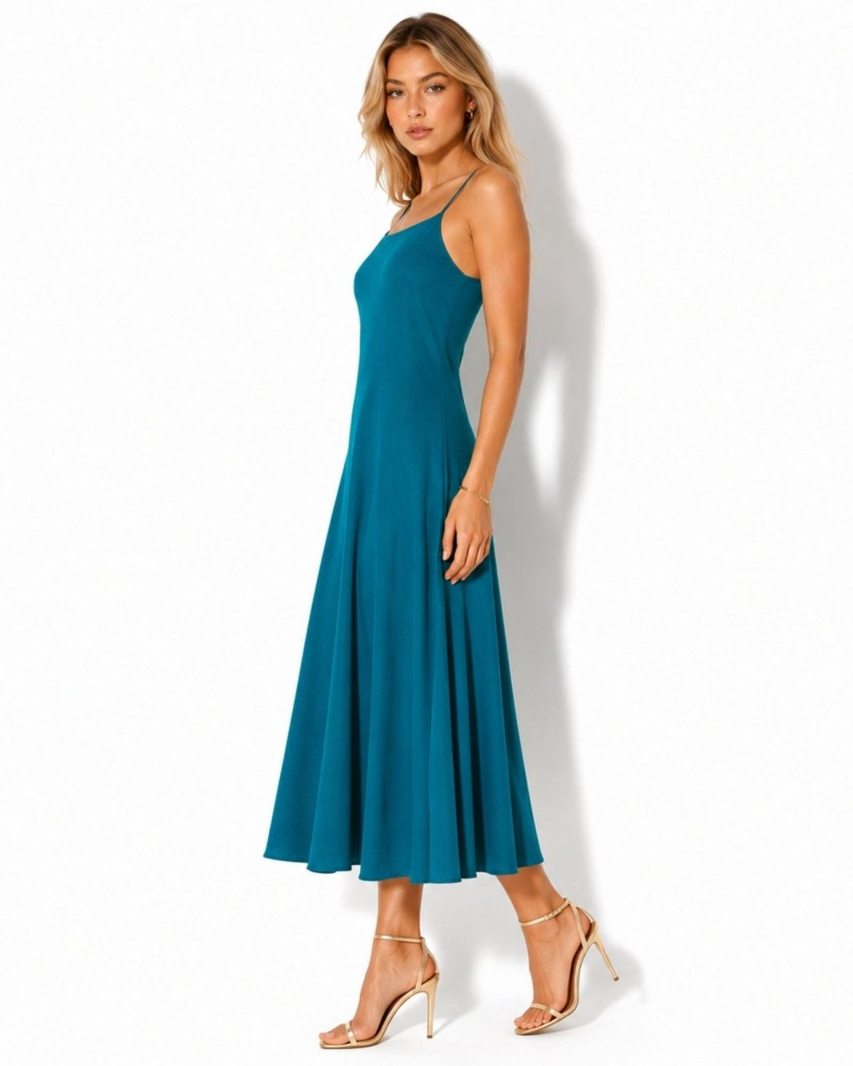 Side profile of a luxury blue a-line midi slip dress with thin spaghetti straps flowing elegantly.