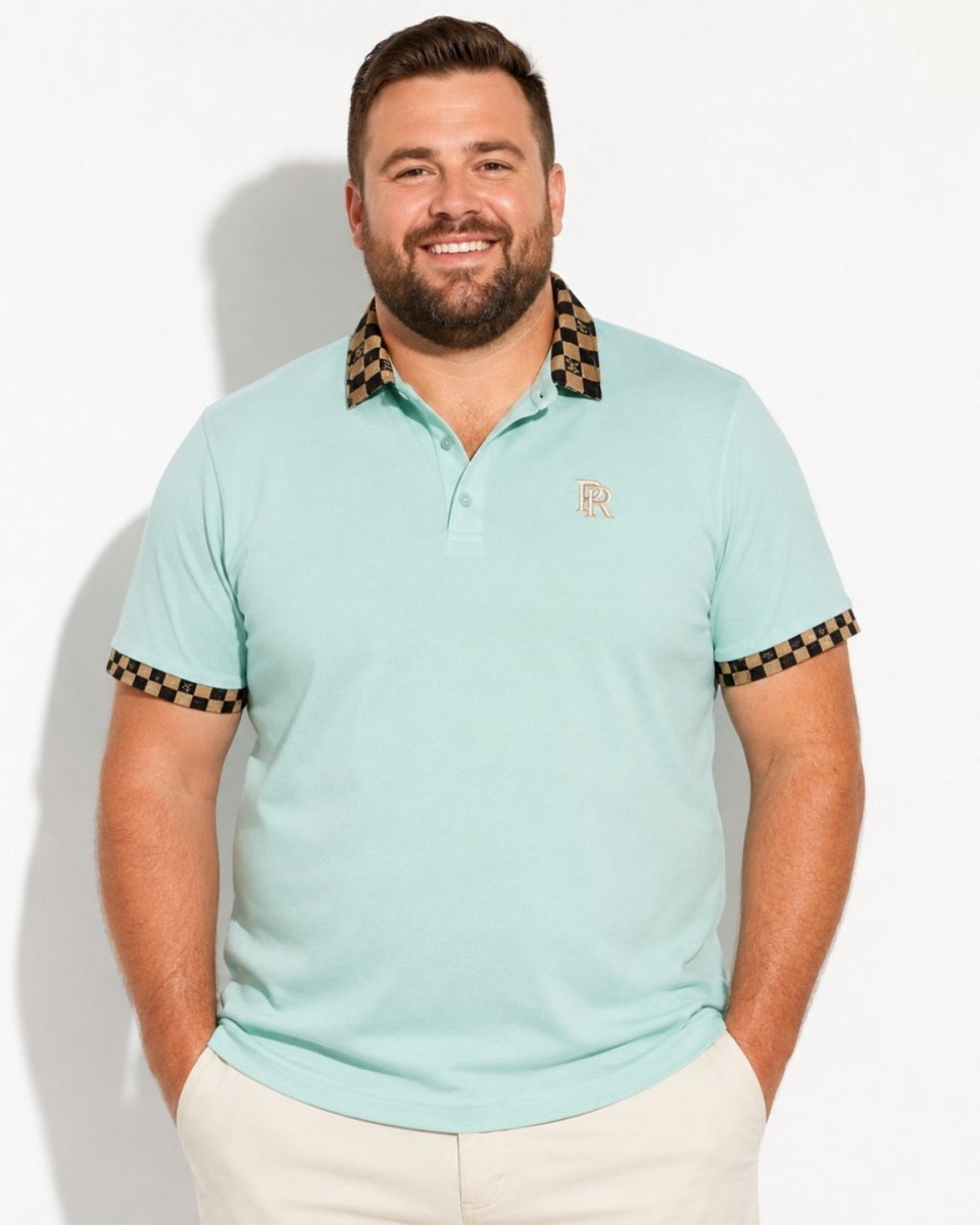 A man wearing a light mint green polo shirt with a brown and black checkered patterned collar and sleeve cuffs, paired with beige pants, standing against a white studio background.
