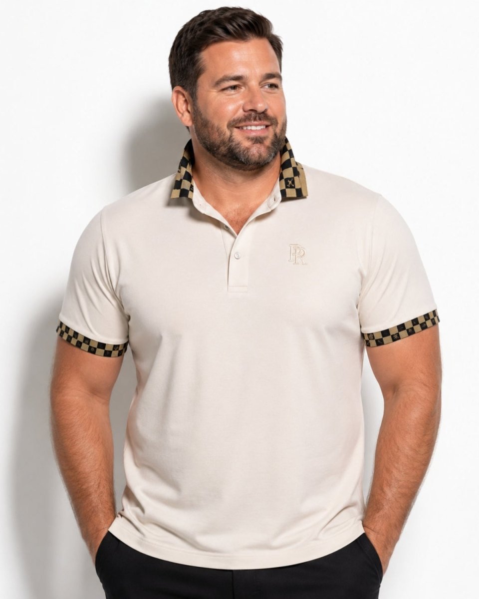 A man wearing a beige short-sleeve polo shirt with a checkered black and gold patterned collar and sleeve cuffs, featuring a small embroidered logo on the left chest.