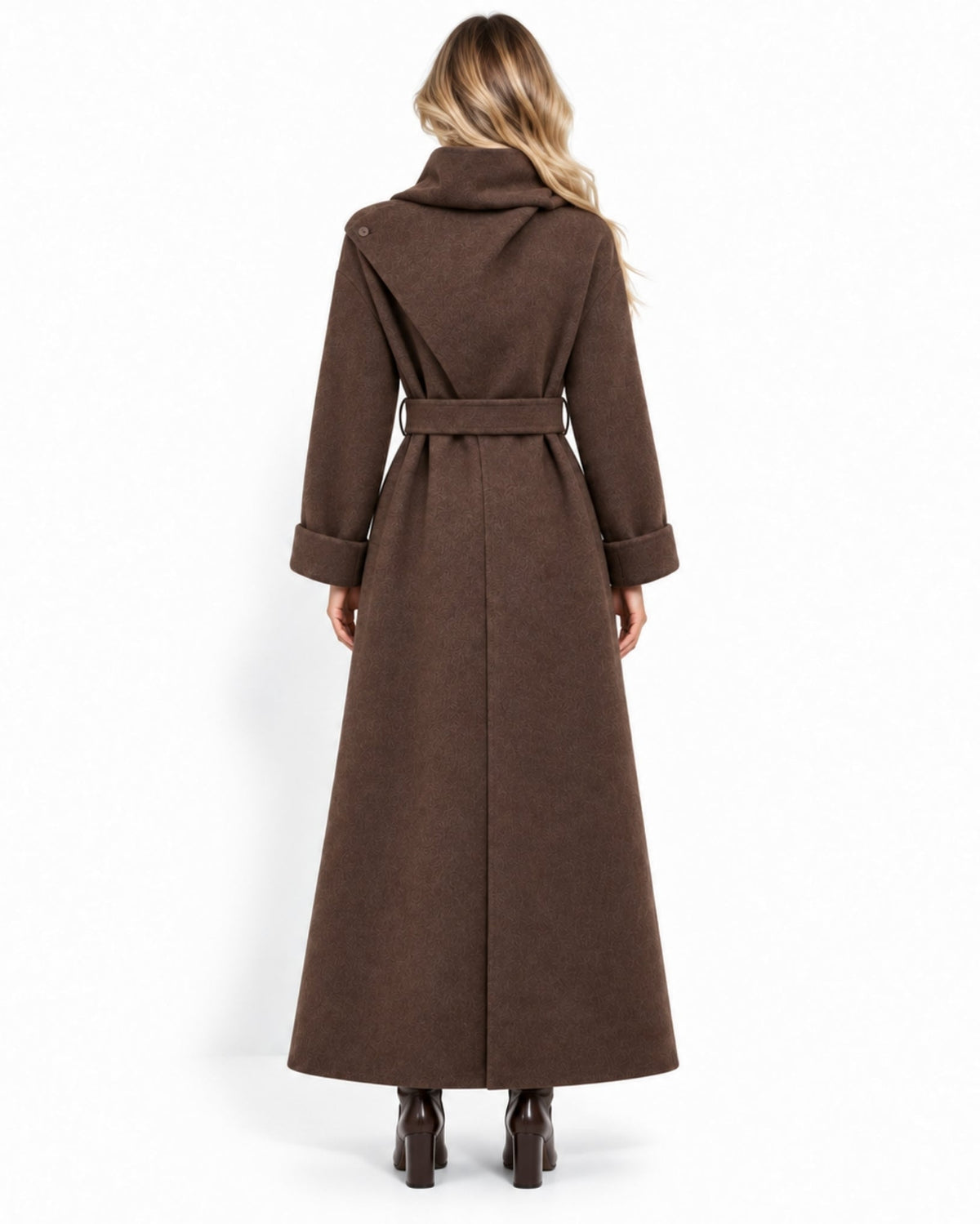 A woman viewed from the back wearing a long brown belted coat with a high collar and wide cuffs, paired with dark heeled boots, against a plain white studio background.