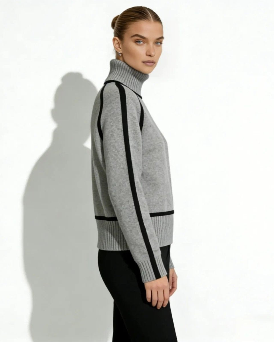Side profile of a woman in a gray high-neck sweater featuring black stripes along the raglan sleeves.