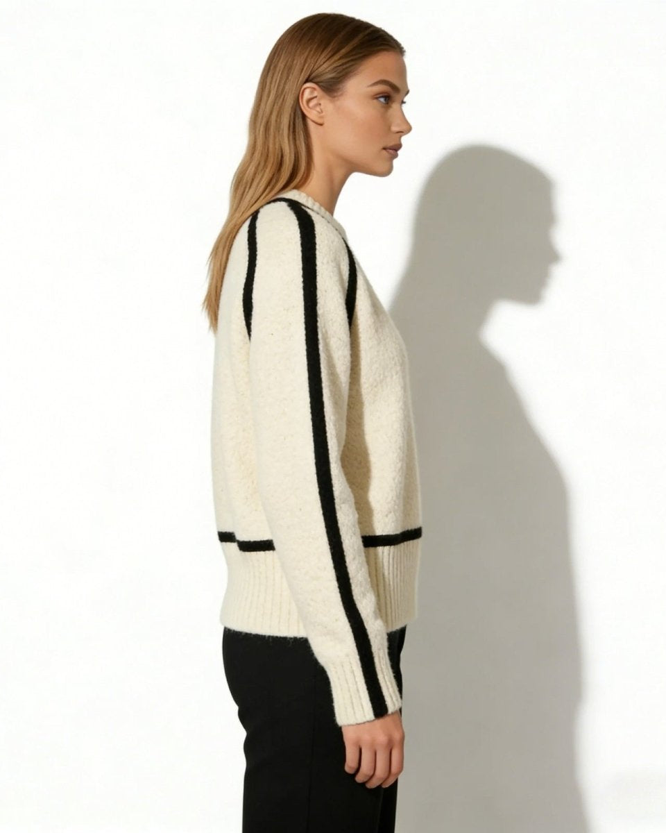 Side profile of a woman in a relaxed-fit white turtleneck showcasing the black raglan sleeve piping detail.