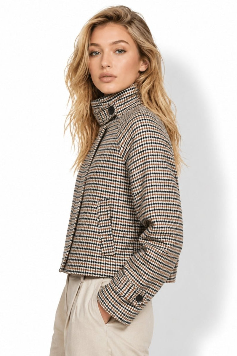 Side profile view of a woman modeling a boxy cropped houndstooth plaid wool blend jacket showing sleeve details and short hemline.