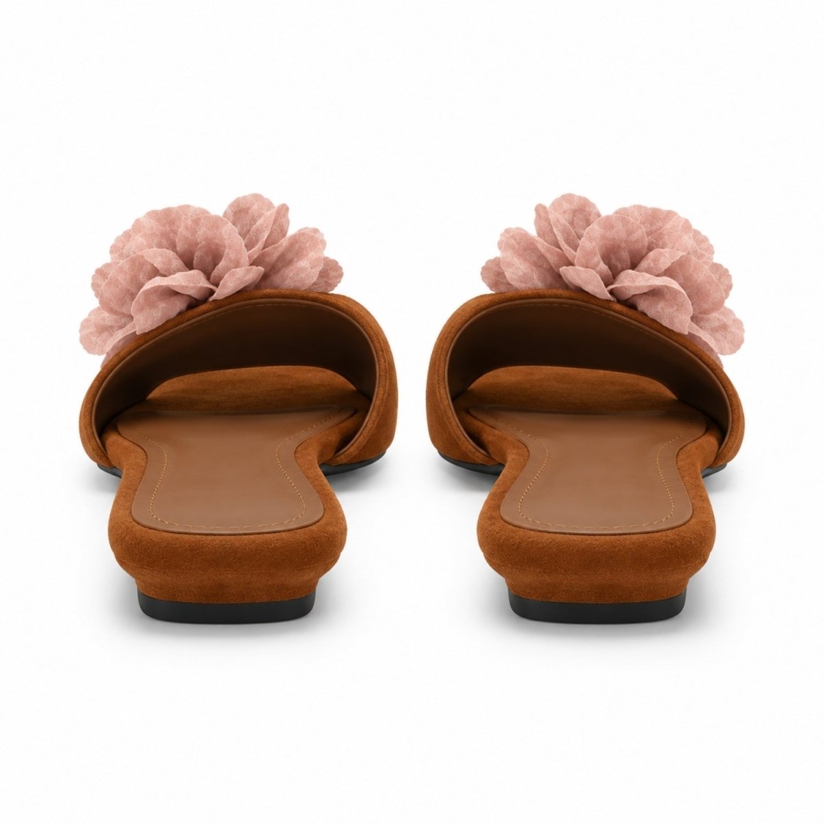 A pair of women's slide sandals viewed from the back, featuring a warm brown suede-like upper with a large dusty pink fabric flower on top, set against a plain white background.