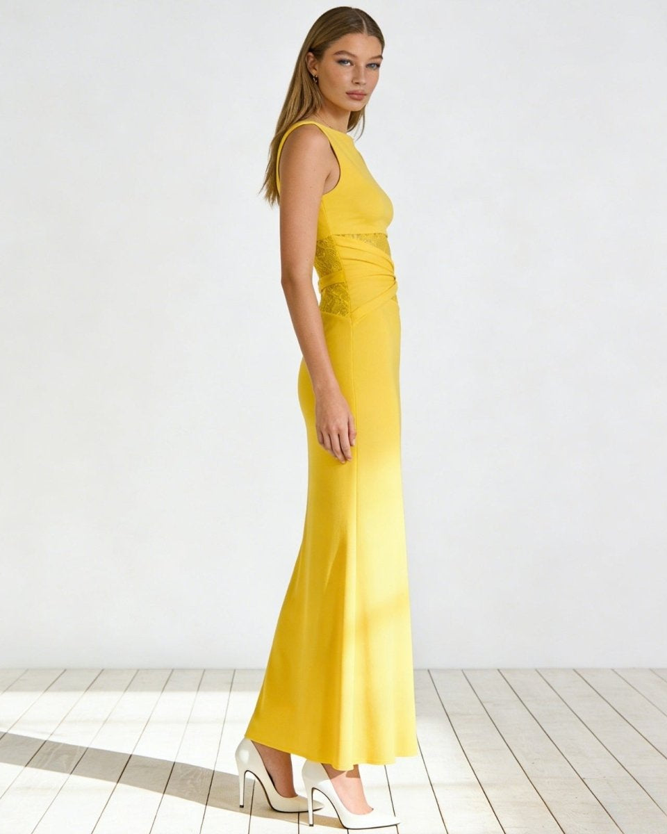 Side profile of a woman in a pale yellow bodycon midi dress showing the asymmetrical lace cut out detail at the waist.