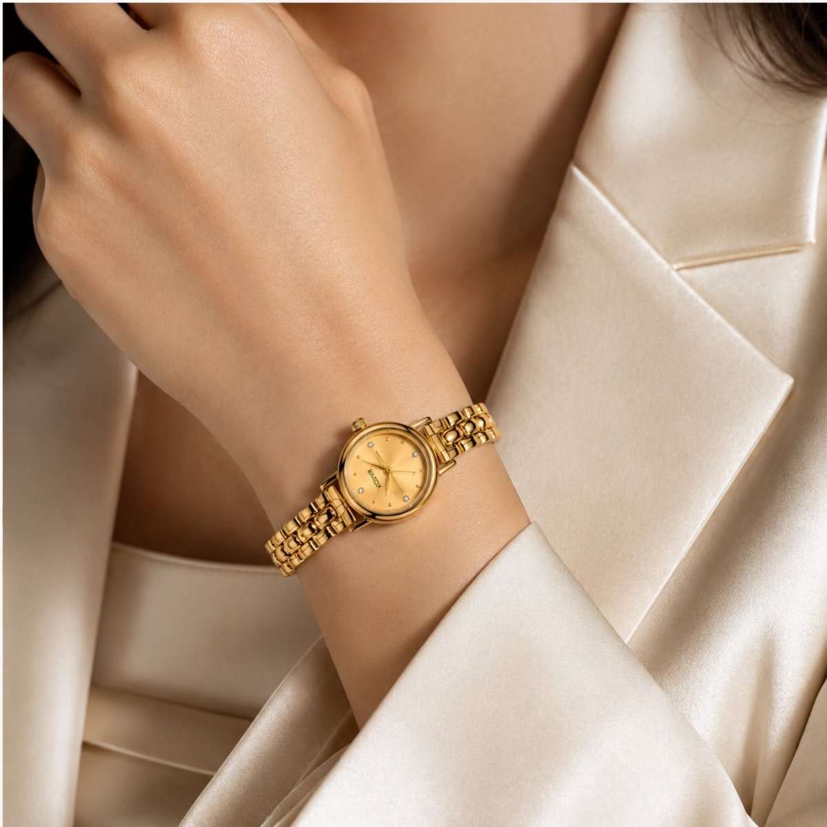 Close up of a woman wearing a silk cream blazer elegantly styling the dainty gold Kouvr vintage wristwatch on her wrist.
