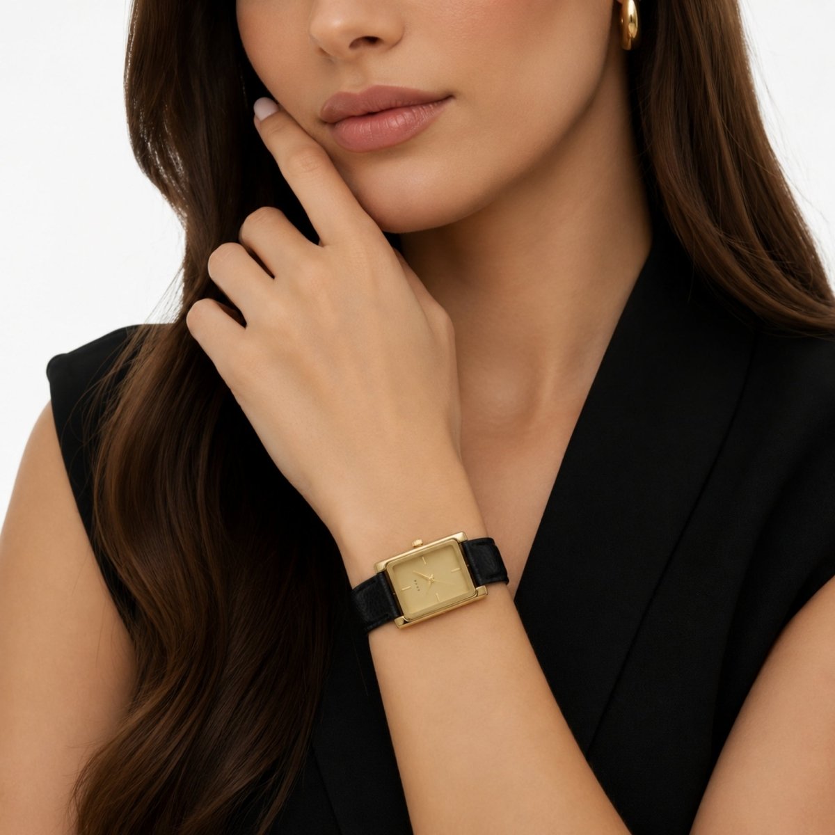 Sophisticated woman in a black elegant dress wearing the Kouvr minimalist rectangular gold tank watch with a black leather strap.