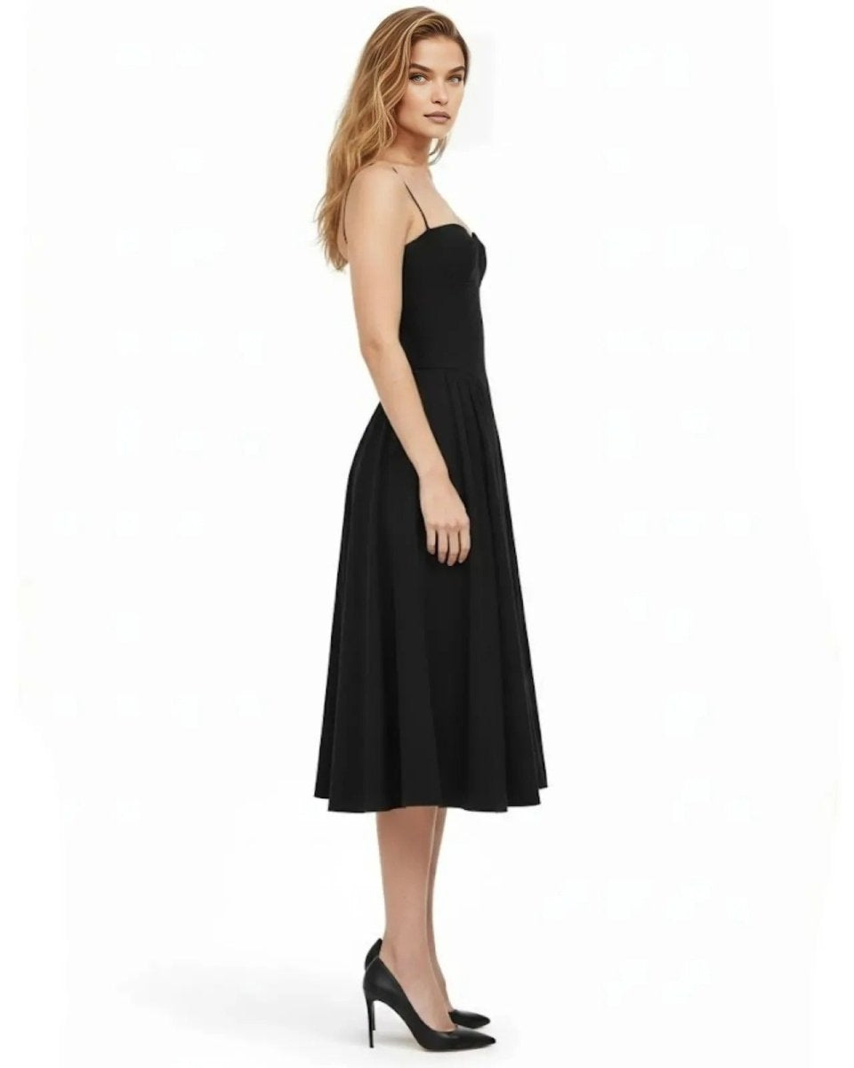 Side profile of a woman in the Evdokia black formal dress, highlighting the cinched waist and elegant midi-length hem.