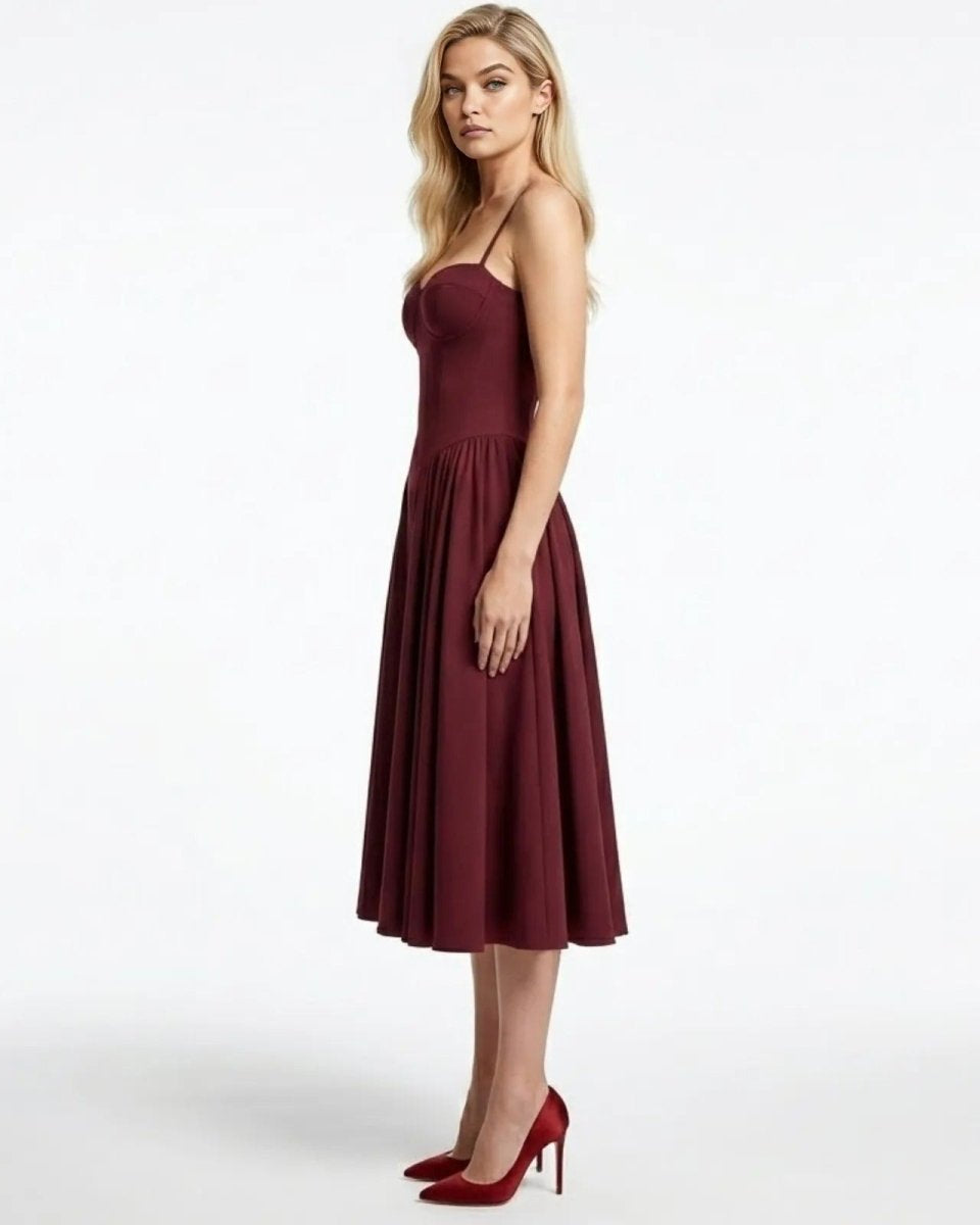 Side view of the Evkodia midi dress in burgundy, showing the fitted corset bodice and pleated skirt silhouette.
