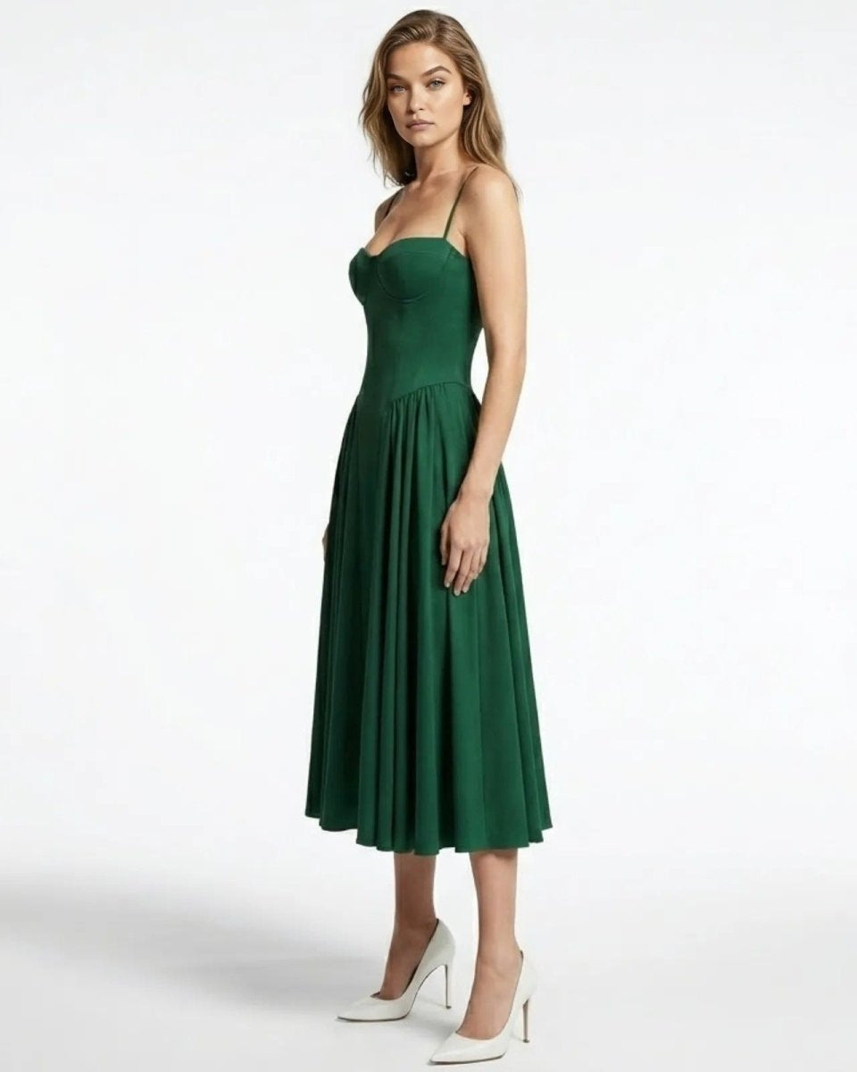 Side profile of a model in the Evdokia emerald green formal dress, showing the fitted waist and drape of the midi skirt.