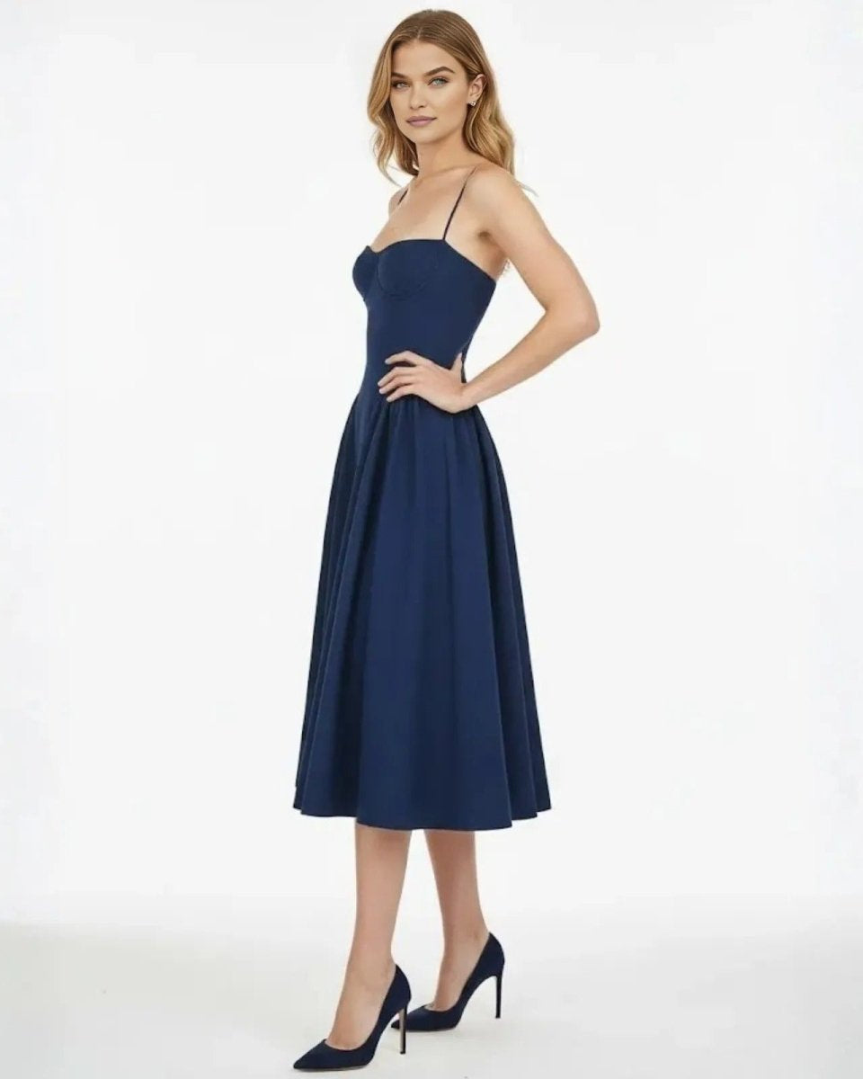 Side view of a model in navy cocktail dress, highlighting the defined waist and A-line silhouette of the midi skirt.